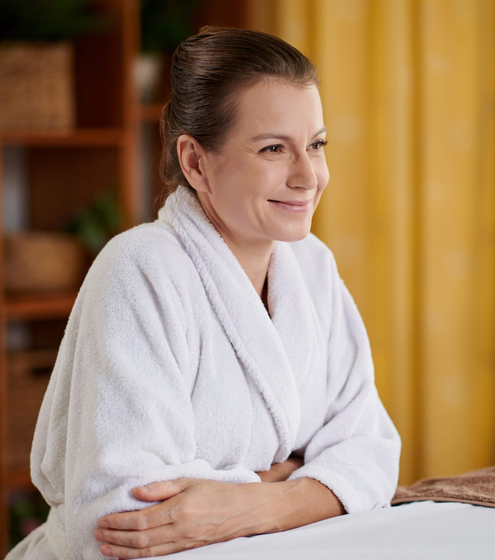 Portrait of positive woman in bath towel excited to get relaxing procedure in spa salon